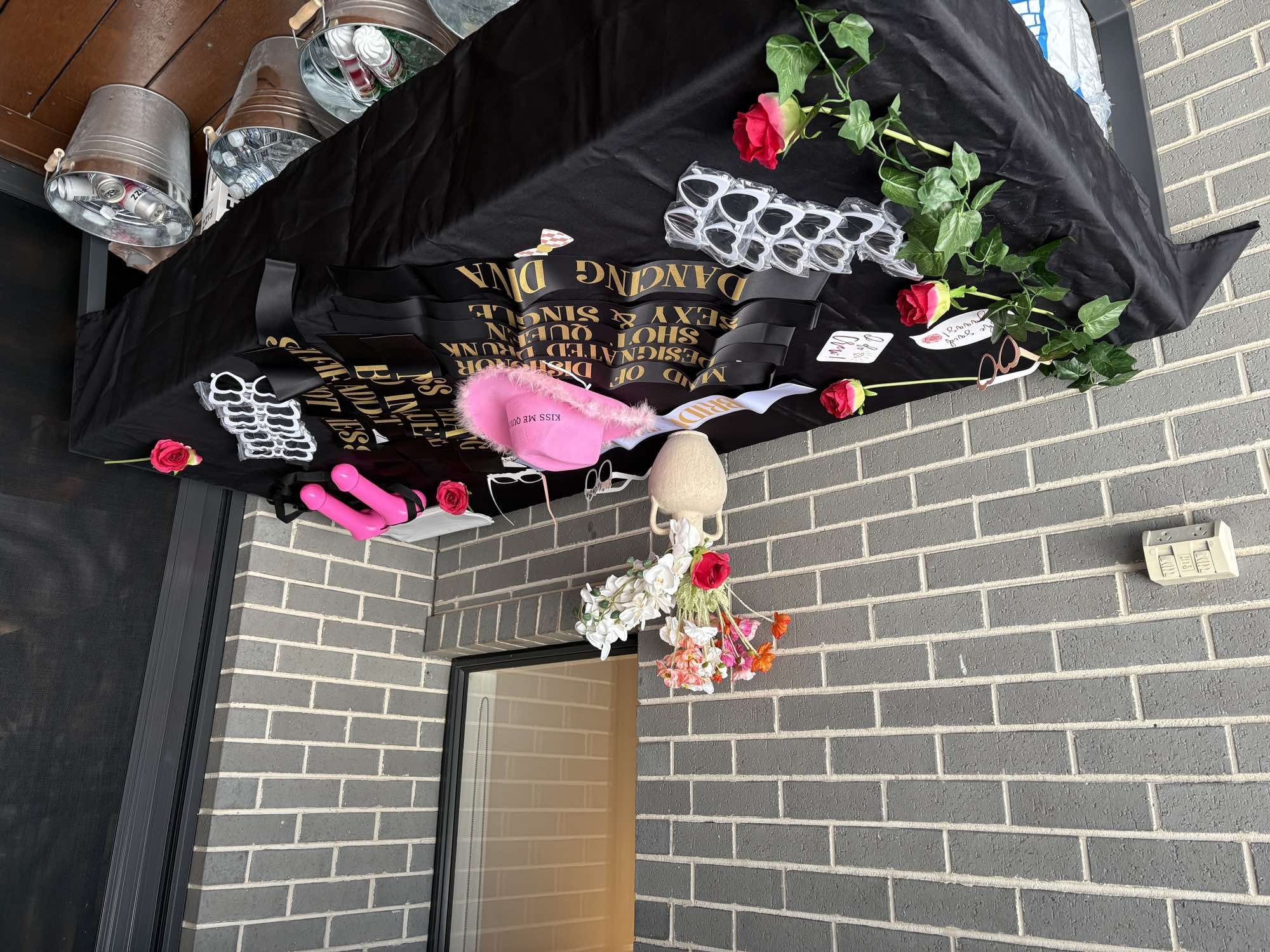 Hens party sashes and accessories laid out on a black table.