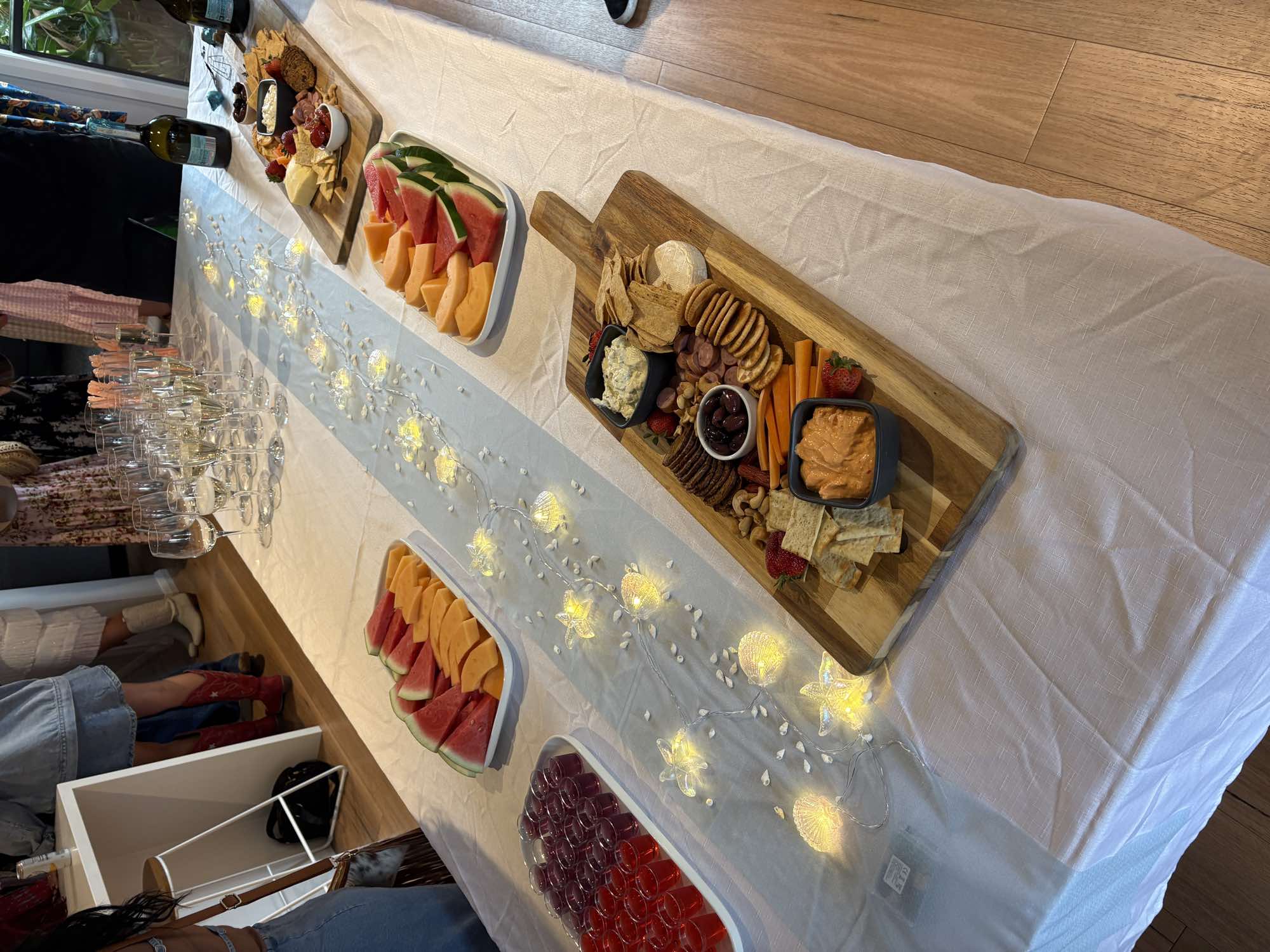 A grazing table with fruit, cheese boards and drinks.